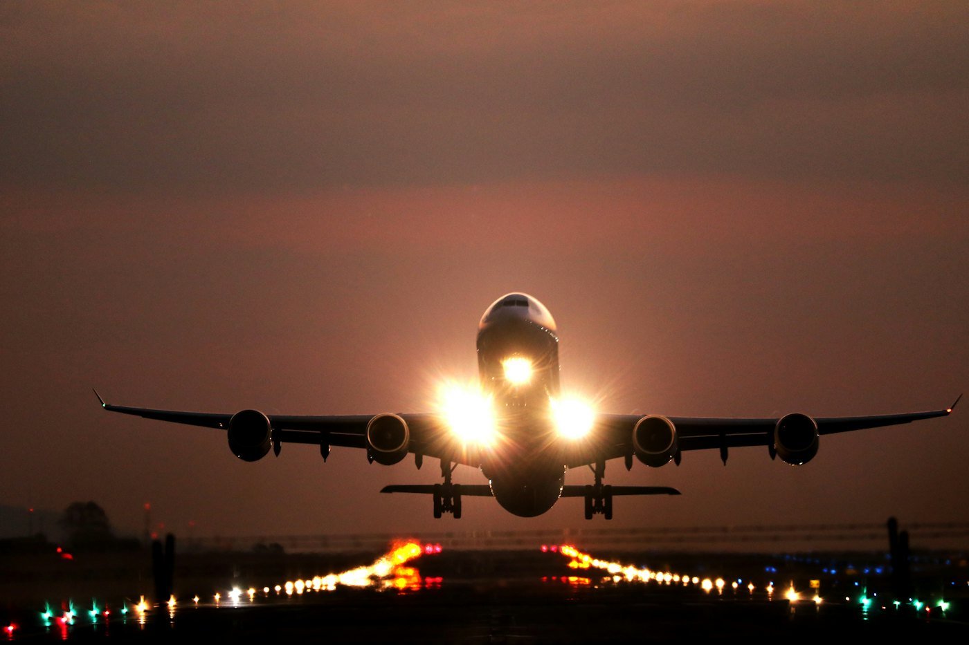 Aircraft lifting off a lit runway at dusk